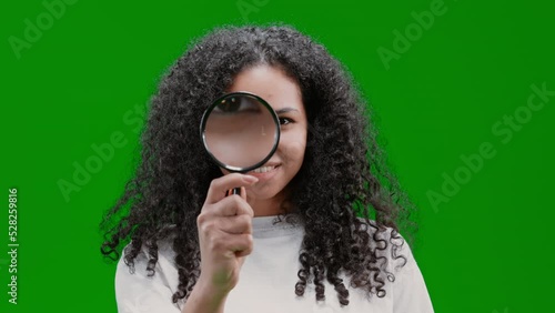 woman with curly long hair dressed white shirt holding magnifying glass looking to the camera and smiling Isolated on Green Screen photo