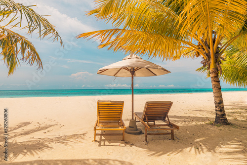 Beautiful tropical sunset  couple beds chairs  umbrella under palm tree. Peaceful romantic landscape horizon  golden sky  calm relaxing exotic. Inspirational beach resort. Couples destination scene