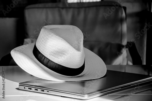 Straw hat on a switched off laptop in a dimly lit room