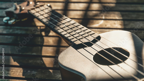 A ukulele on a wooden table in sunset light