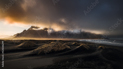 Panoramic sunset view of black sand dunes at Stokksnes and cloud-covered mount Vestrahorn. South-East Iceland. photo