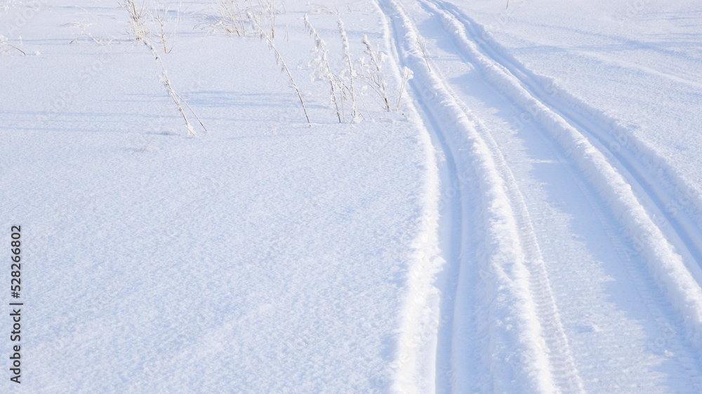 Track of traces from a snowmobile in drifts of white snow. Nature and outdoor. Winter theme wallpaper or background Track of traces from a snowmobile in drifts of white snow. Nature and outdoor. Winter theme wallpaper or background
