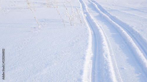 Track of traces from a snowmobile in drifts of white snow. Nature and outdoor. Winter theme wallpaper or background © Deacon docs