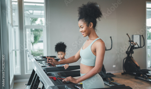 Healthy woman running on sports treadmill with daughter.Exercise for health and body health, to practice sports.children running on sports treadmill in gym.