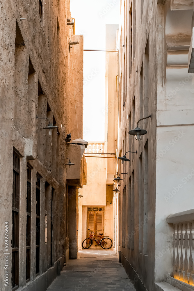 Bicycle next to the wall in old market in Doha, perspective form the end of the narrow street.