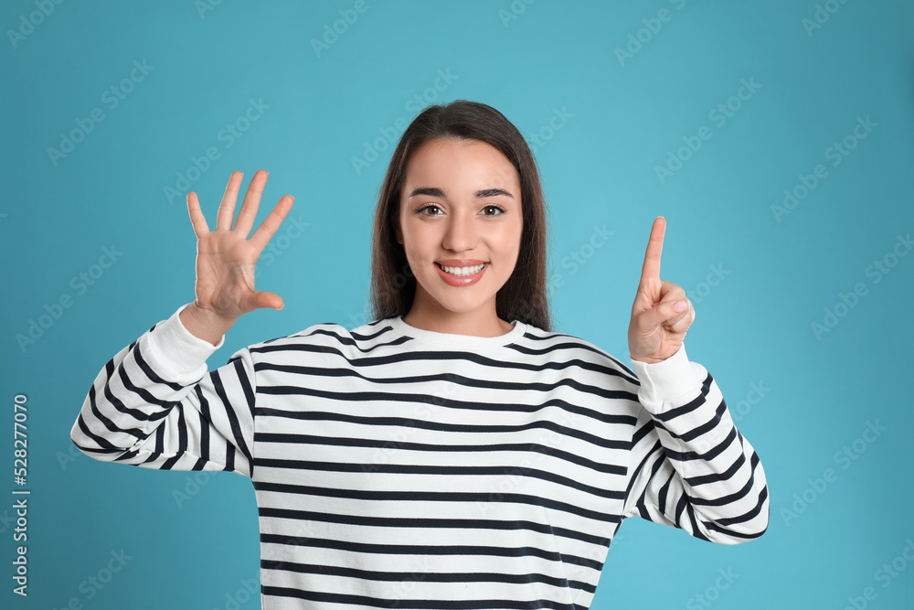 Woman showing number six with her hands on light blue background Woman showing number six with her hands on light blue background
