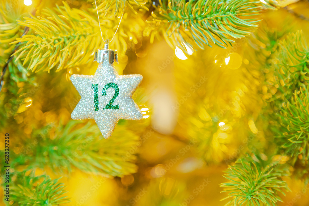 Weihnachtsschmuck (Stern) am Baum mit einer Zahl (12) vom Weihnachtskalender