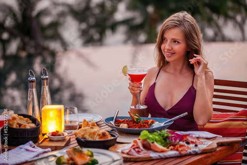 Happy young lady with a glass of cocktail in fine dining outdoor restaurant
