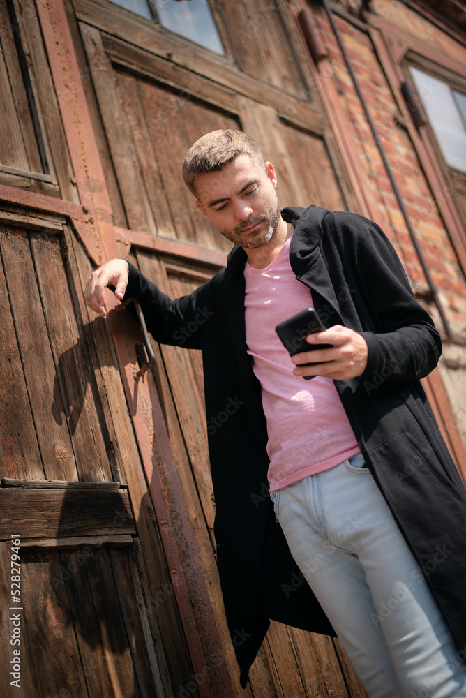 Young man in the black cardigan and mobile phone in hands walks in the city. Young man in the black cardigan and mobile phone in hands walks in the city.