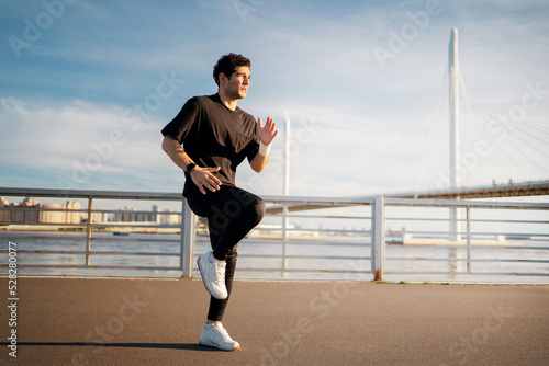 Male runner training runs in sportswear and sneakers, fitness watch on hand to measure the result