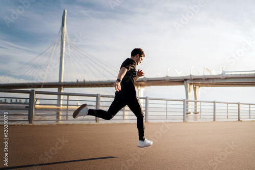 Male runner training runs in sportswear and sneakers, fitness watch on hand for calorie counting © muse studio