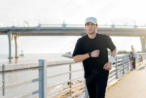A runner training runs in sports clothes, a man fitness watch on his arm to measure the result