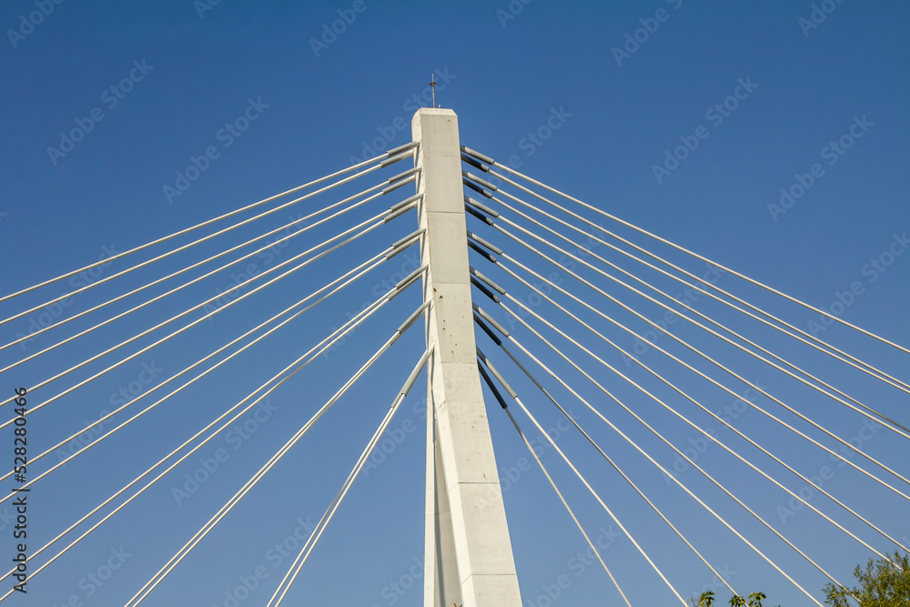 Metal strings of an architectural bridge against a blue sky