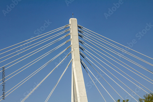 Metal strings of an architectural bridge against a blue sky