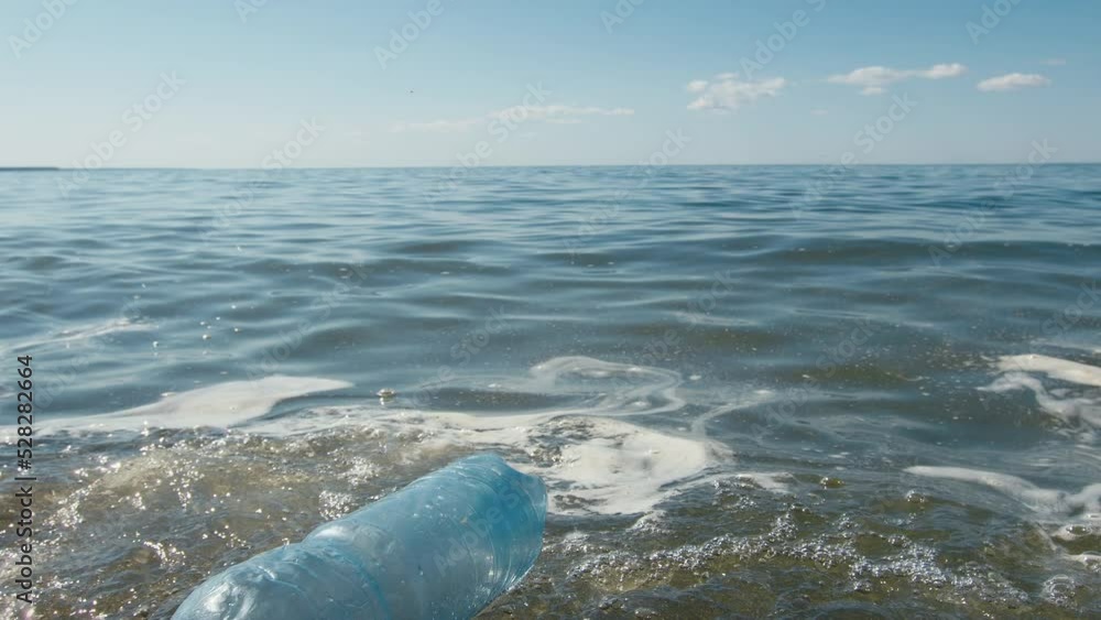 Plastic bottle floats in water near seashore. Environmental and ecological pollution, garbage sorting concept Plastic bottle floats in water near seashore. Environmental and ecological pollution, garbage sorting concept