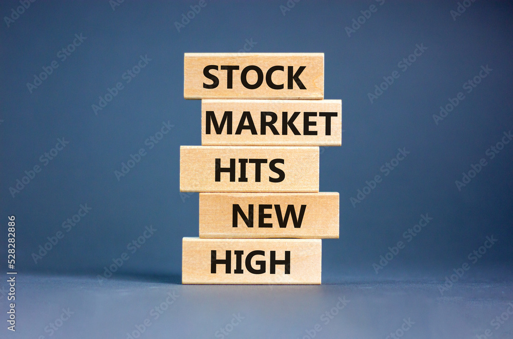Stock market hits new high symbol. Concept words Stock market hits new high on wooden blocks on a beautiful grey table grey background. Business and stock market hits new high concept. Copy space.