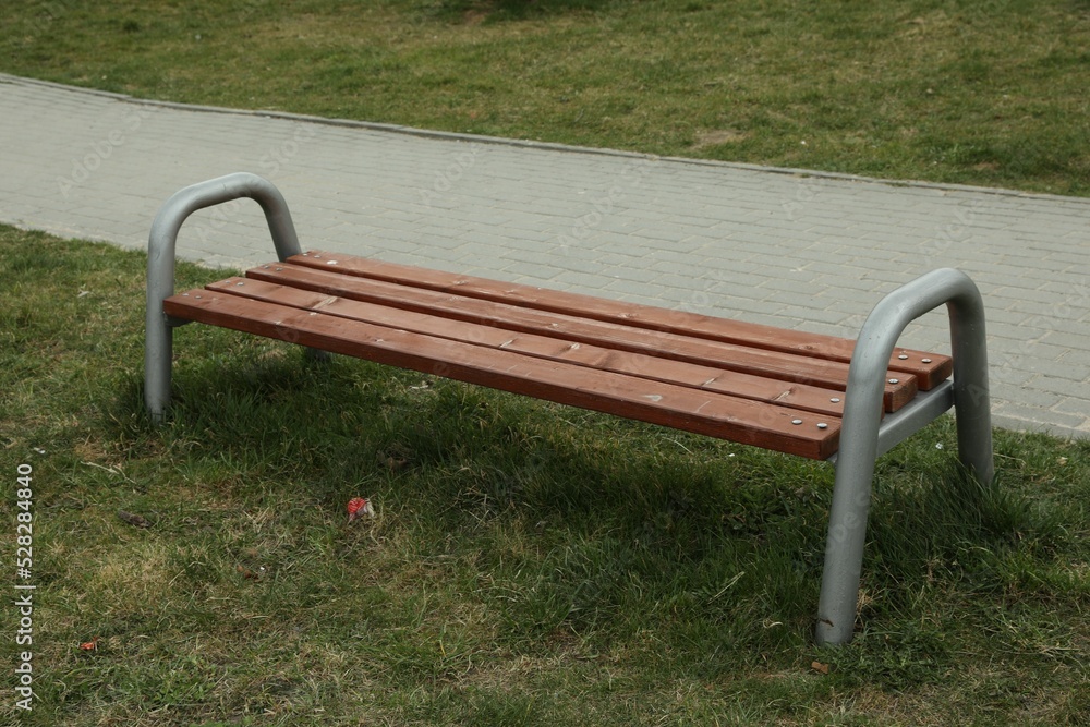 Modern wooden bench on green grass outdoors