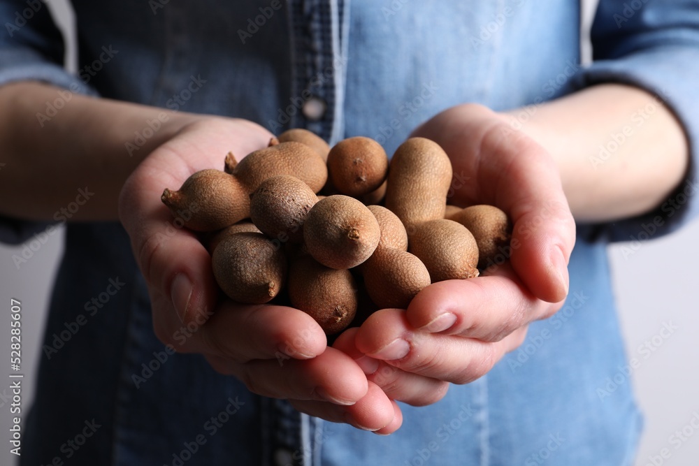 Woman holding fresh ripe tamarinds, closeup view Woman holding fresh ripe tamarinds, closeup view