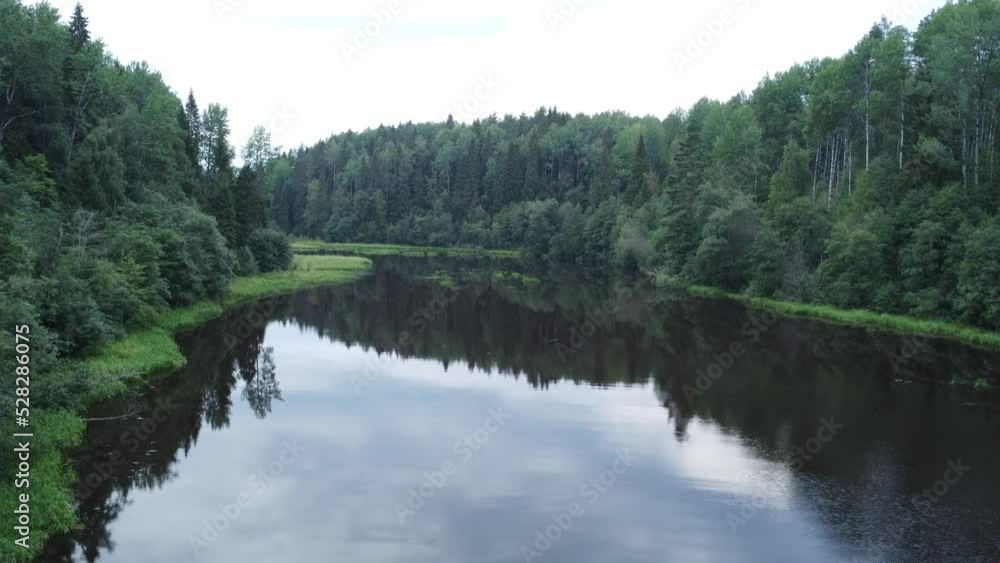 A small river flowing between low swampy banks. Islets of grass are visible in the center of the river. A small river flowing between low swampy banks. Islets of grass are visible in the center of the river.
