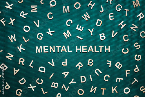 Mental health word from wooden letters. Mental health text on green background with many other letters.