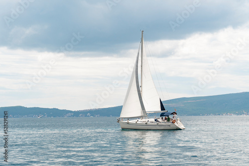 A large white sailing yacht for tourists in a blue sea against a clear sky. Tourist sailing boat. Water transport for tourists.