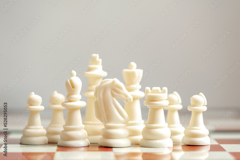 White chess pieces on a chessboard on a neutral background