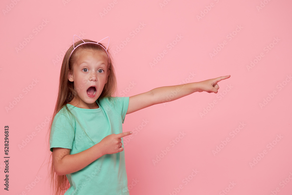 Portrait of surprised cute little toddler girl child over pink background. Looking at camera. Points hands to the right side. Advertising childrens products. Portrait of surprised cute little toddler girl child over pink background. Looking at camera. Points hands to the right side. Advertising childrens products.