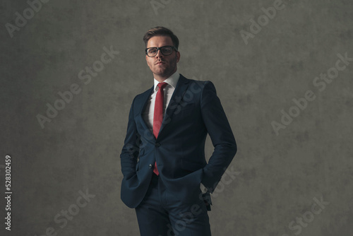 attractive man with hands in pockets confidently posing in studio