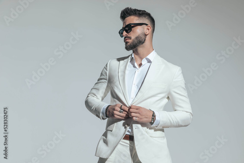 Photo bearded businessman with sunglasses buttoning white suit