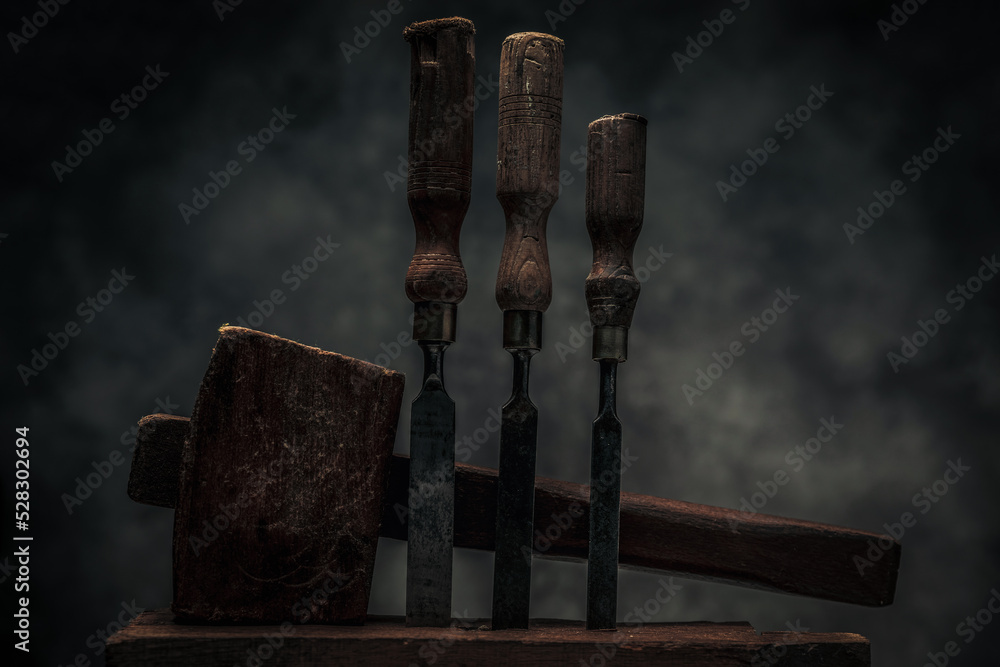 collection of old rusty carbon steel chisels with carving hammer behind collection of old rusty carbon steel chisels with carving hammer behind