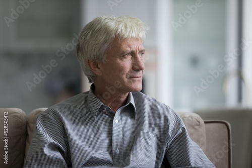 Fotografie Thoughtful sad senior elder man sitting on home couch, looking away, thinking ov
