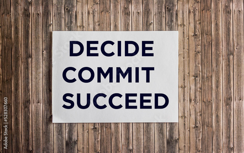 Conceptual hand writing showing DECIDE COMMIT SUCCEED on notepad and wooden background. Achievement of the goal. Reach your dreams.