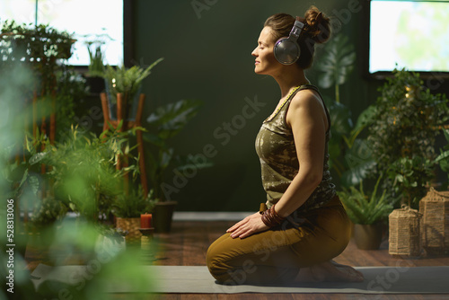 Fototapeta Naklejka Na Ścianę i Meble -  relaxed stylish 40 years old woman at green home doing yoga