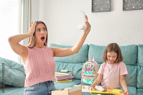 mother and daughter sitting on the sofa at home. Daughter very happy with her school materials and mother worried about what she has spent buying them and the rise in prices