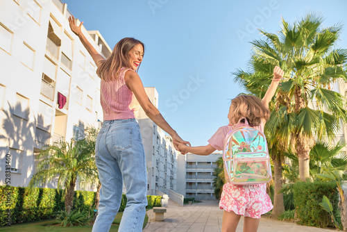 mother and daughter walking down the street to go to school