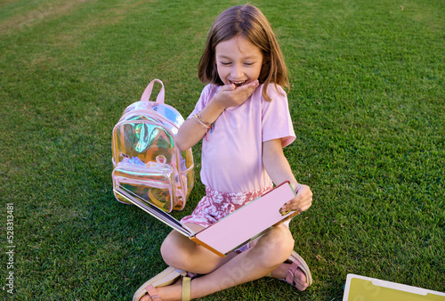 girl sitting on the grass reading a book having fun and learning outdoors