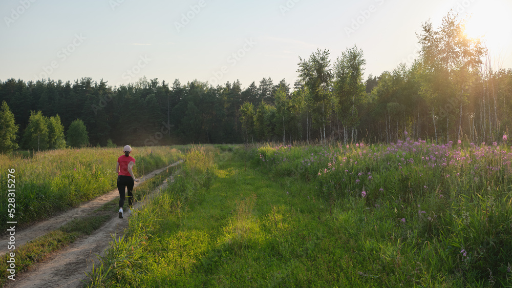 Young woman running on a rural road during sunset. Lifestyle sports background.