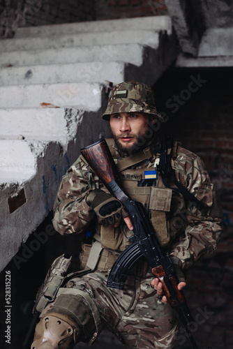 A Ukrainian military man poses against the background of destroyed buildings. The war between Ukraine and Russia