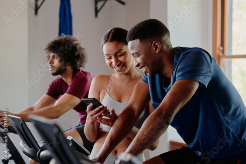 Group of happy young multiracial friends using mobile phone at the gym
