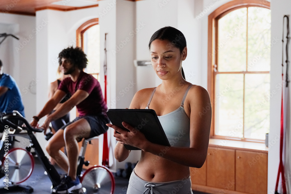Professional biracial young woman using digital tablet at the gym Professional biracial young woman using digital tablet at the gym