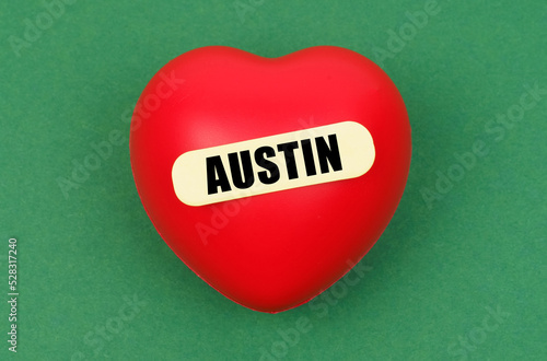 On a green surface lies a red heart with the inscription - Austin