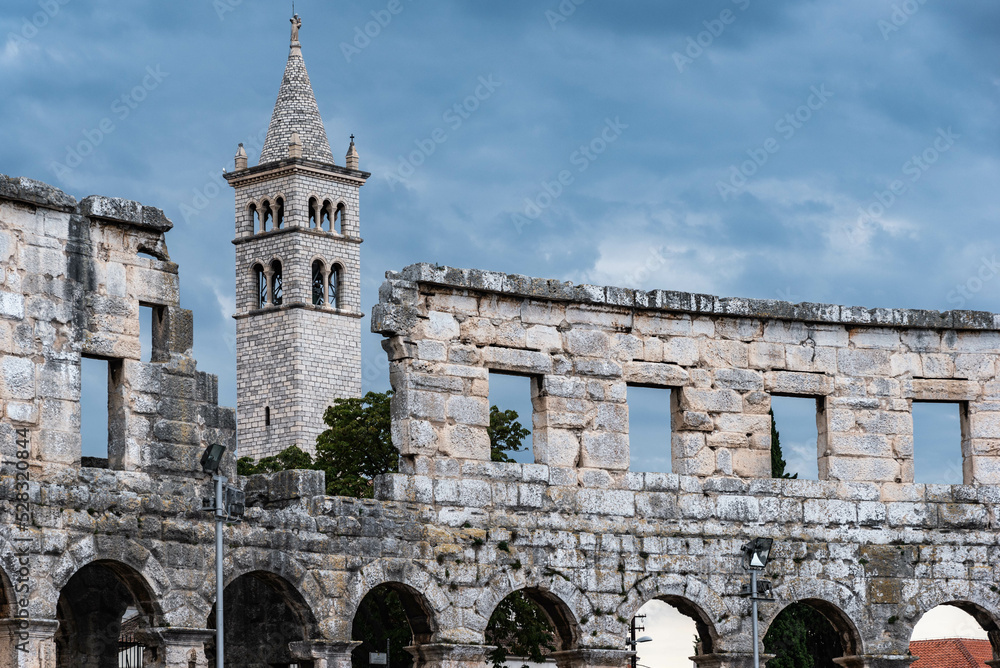 clock tower of a church behind the roman amphitheater in pula, croatia