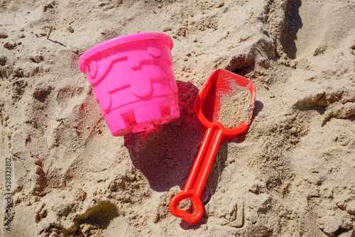 Children's bucket and spade beach toys on sandy beach. colorful bucket and shovel in the sand. items for building sandcastles 