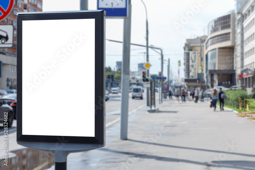Vertical billboard for advertising and text in the city. Blured wide sidewalk with pedestrians during the day. Mock-up.