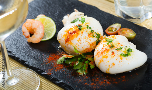 Seafood. Two roasted cuttlefishes served with savory sauce and prawns garnished with greens and lemon