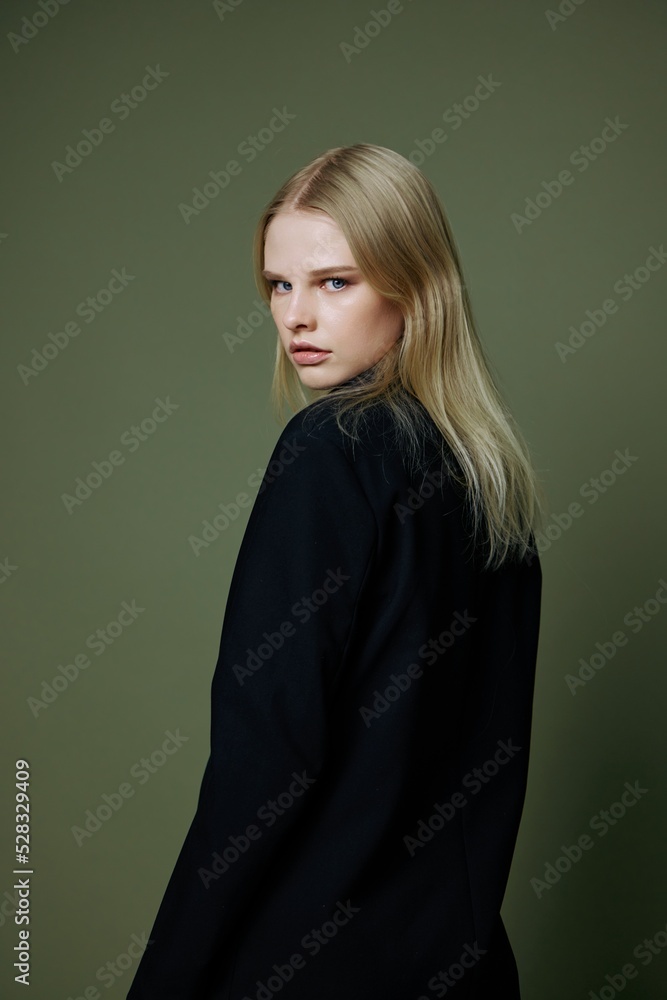 Art fashion photo shoot. An amazing stunning stylish girl in a designer suit half-turns to look at you in the camera posing on a green olive background in the studio Art fashion photo shoot. An amazing stunning stylish girl in a designer suit half-turns to look at you in the camera posing on a green olive background in the studio