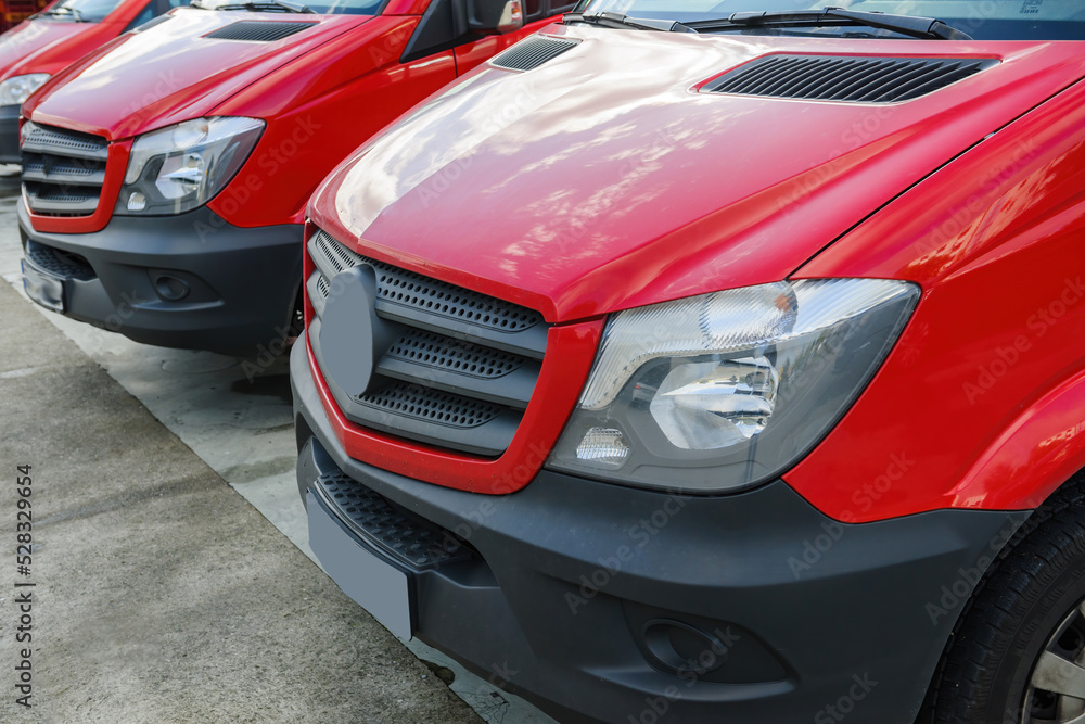 Close-up of row of red delivery vans parked in front of distribution warehouse center