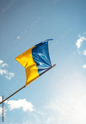 peacefully waving Flag of Ukraine - Prapor Ukrainy with equally sized horizontal bands of blue and yellow - blue sky with few clouds in background