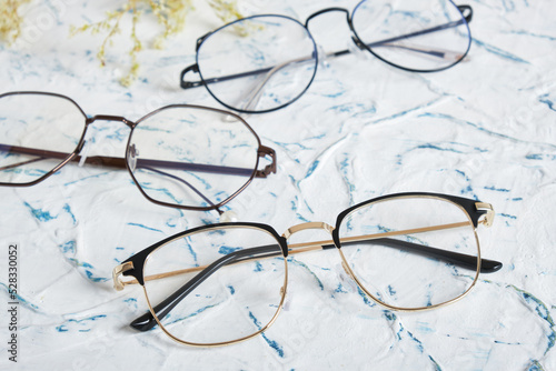 Woman's eyeglasses and little yellow flowers branches on textured background. Flat lay