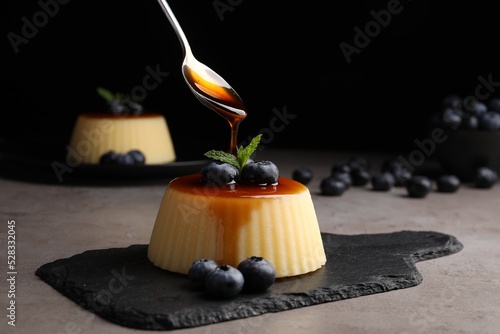 Photography Pouring caramel onto delicious pudding with blueberries and mint on grey table a